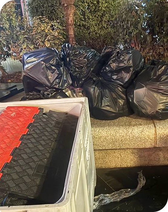 Black rubbish bags collected during an event waste removal service, loaded near a clearance van.