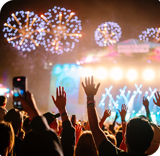 Outdoor music festival crowd with stage lights and fireworks