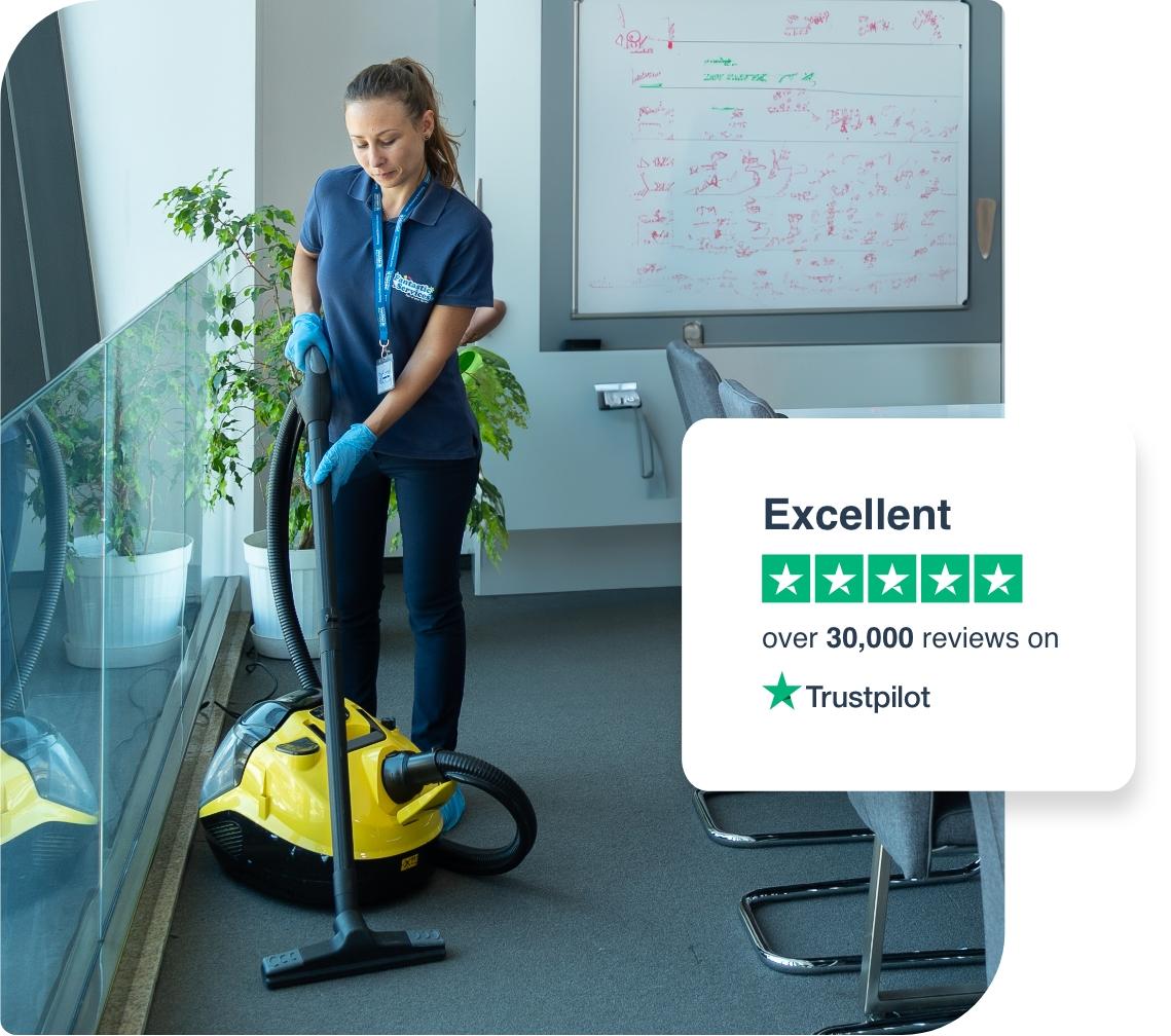 hotel-carpet-cleaning A professional cleaner in a blue shirt and gloves is vacuuming a carpet.