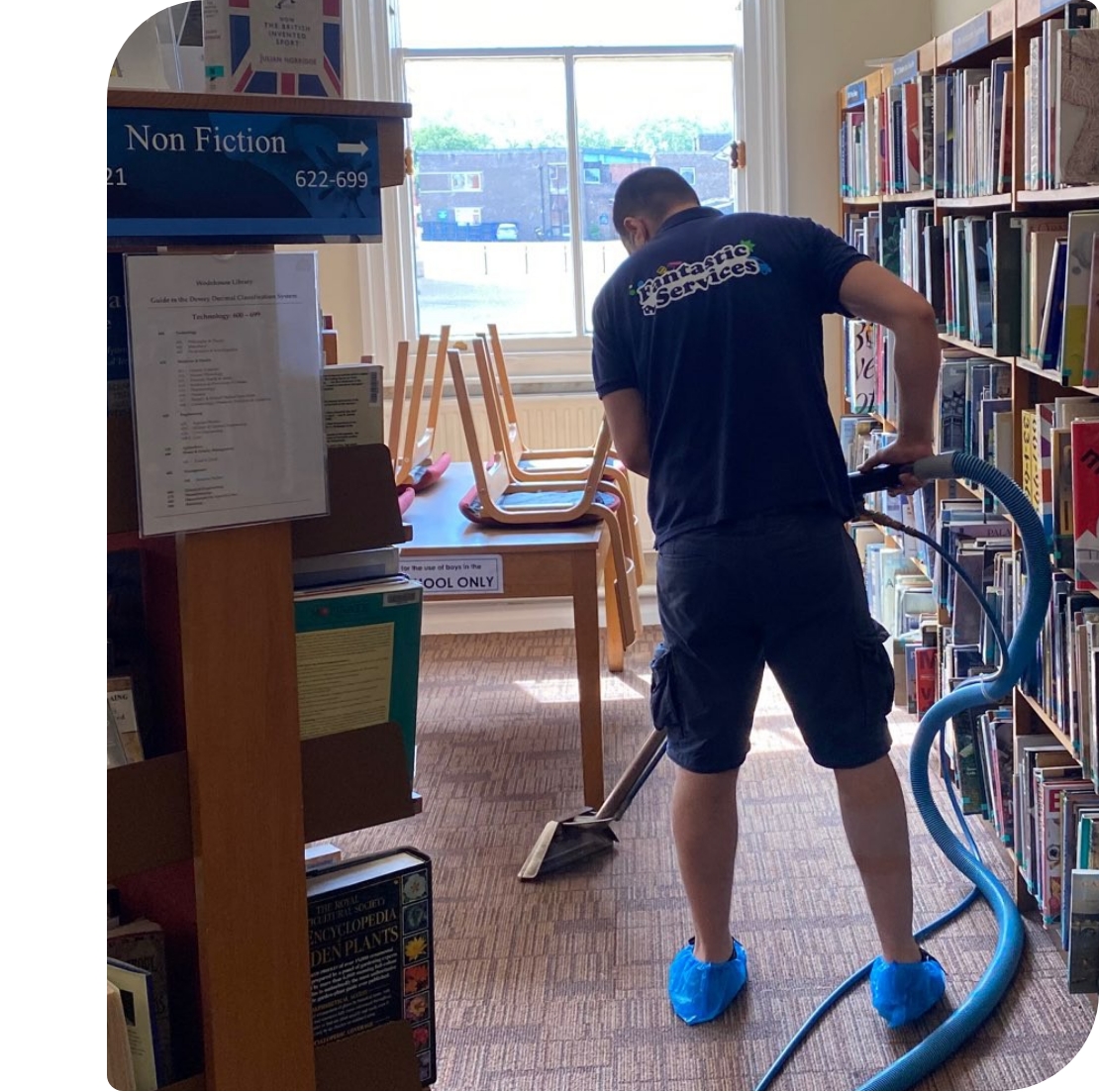 Professional-carpet-cleaning A commercial carpet technician in a dark uniform and blue shoe covers is cleaning a carpet.