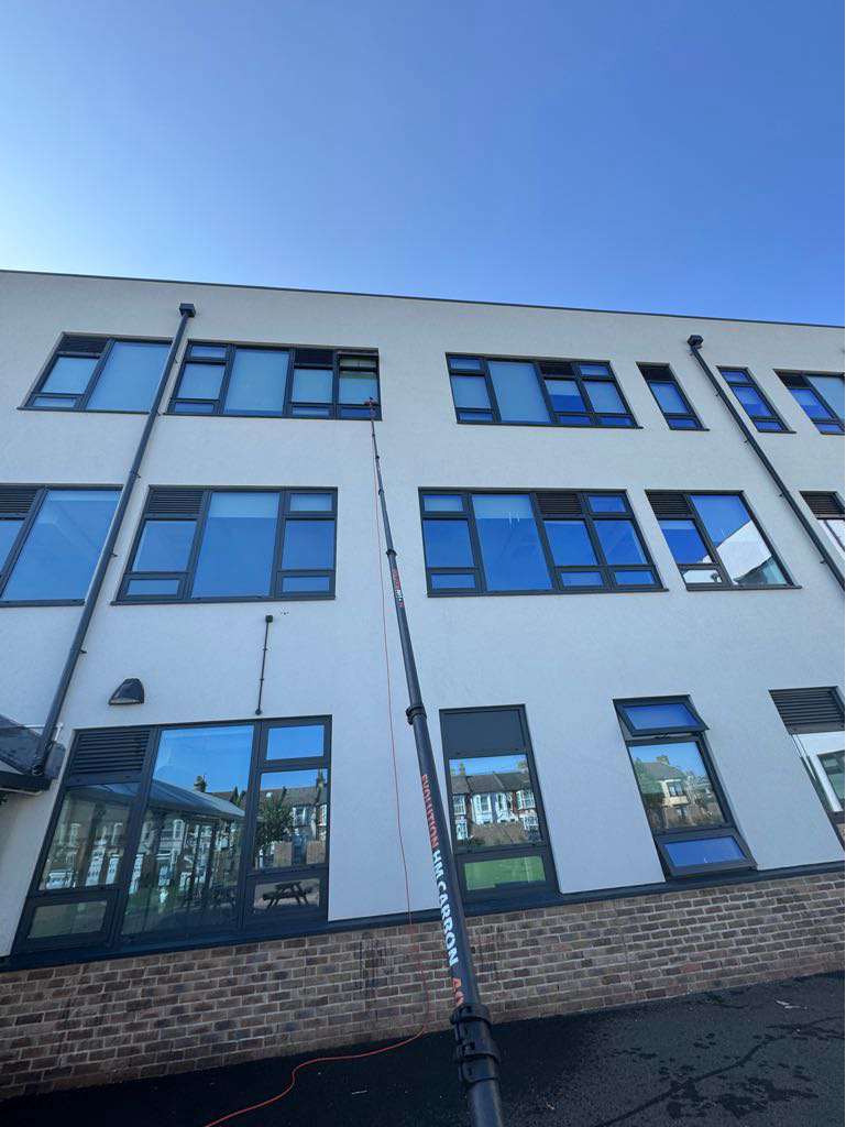 Picture of extendable water-fed pole system during cleaning of high windows on a modern commercial building