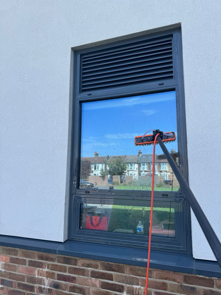 Water-fed pole with brush head cleaning a commercial building window