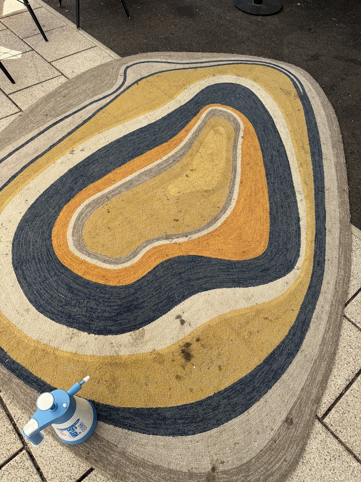 A multicoloured rug with visible dirt and stains before professional rug cleaning service.
