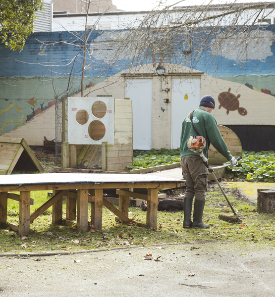 outdoor-play-area-before Gardener trimming and maintaining grass in a children’s outdoor play