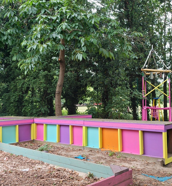 brightly-repainted-playground-structure Colourful refurbished play structure at Lady Allen Adventure Playground, surrounded by trees and outdoor play equipment.