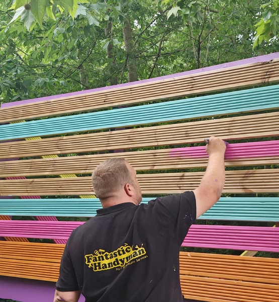 lady-allen-playground-colourful-fence-painting Fantastic Services handyman painting a colourful wooden fence during the refurbishment of Lady Allen Adventure Playground.