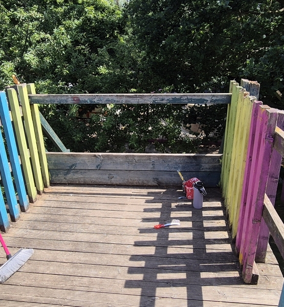 lady-allen-playground-platform-deck-refurbishment Colourfully painted wooden platform deck at Lady Allen Adventure Playground during refurbishment work, with painting tools visible on the floor.
