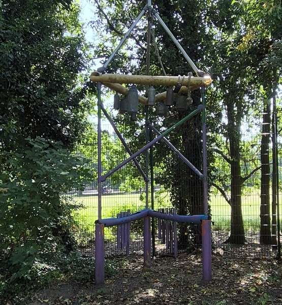 sensory-music-frame Outdoor sensory music frame with hanging bells surrounded by trees.