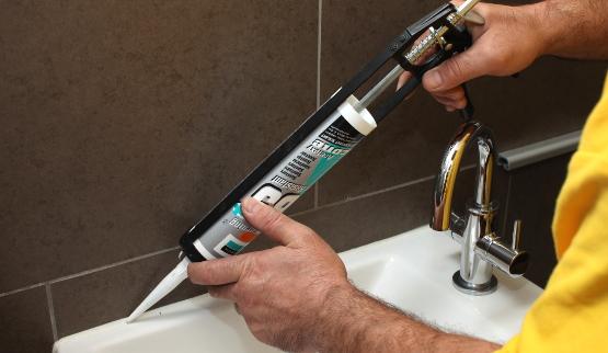 Technician grouting tiles in a bathroom.